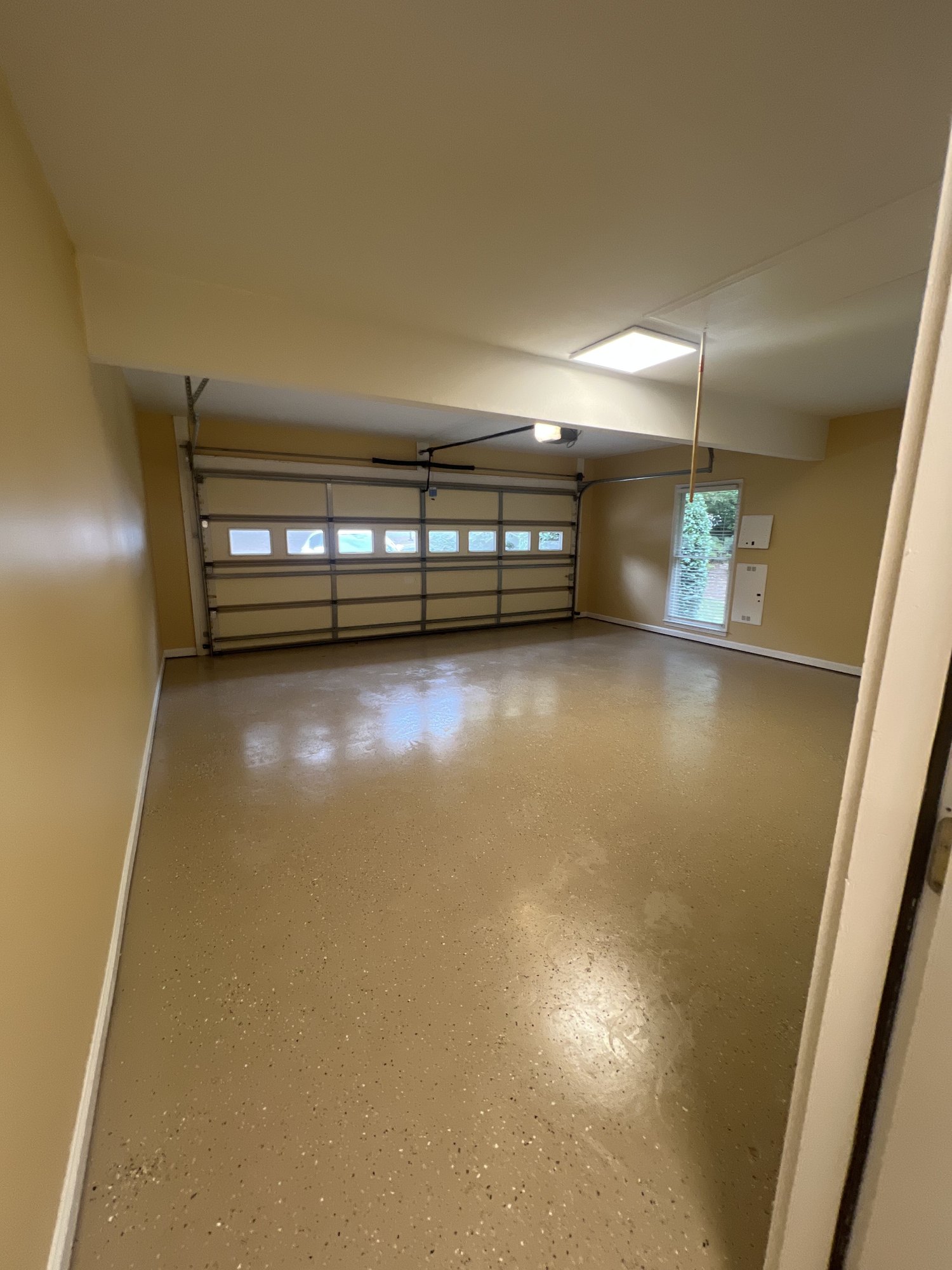 Garage with a smooth, lightly speckled floor finish beneath a closed garage door