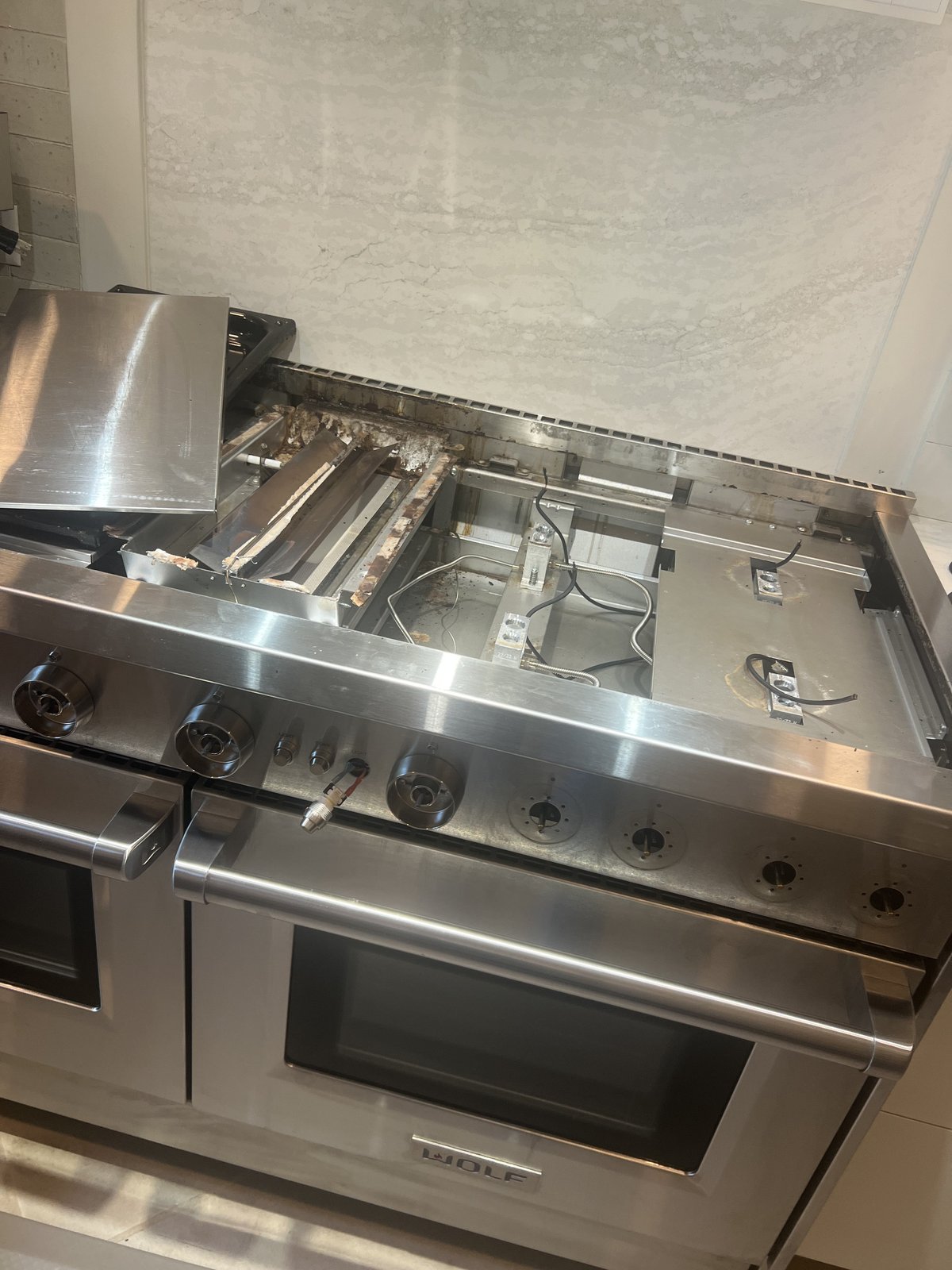 Wolf range with cooktop components removed to access the internal parts during service.